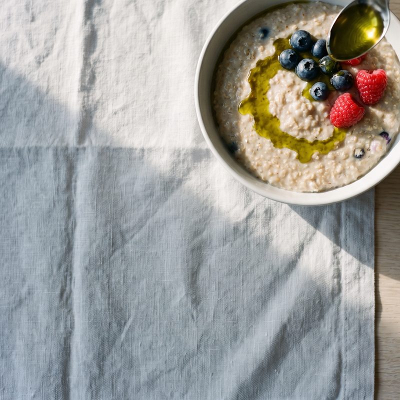 Golden hemp oil drizzled over a bowl of porridge with berries in morning light