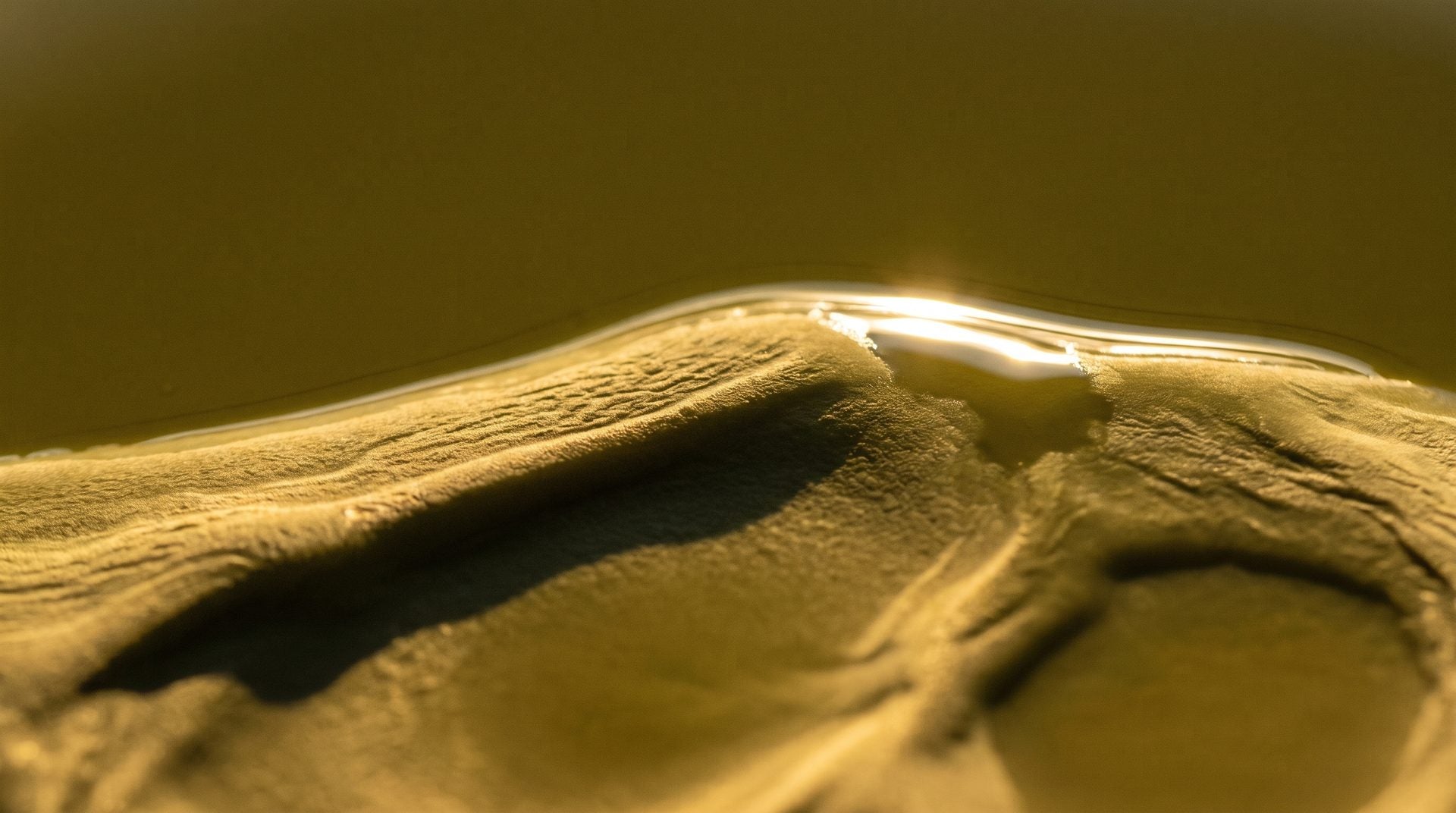 Macro of golden cold-pressed hemp oil, its surface rippling like dunes