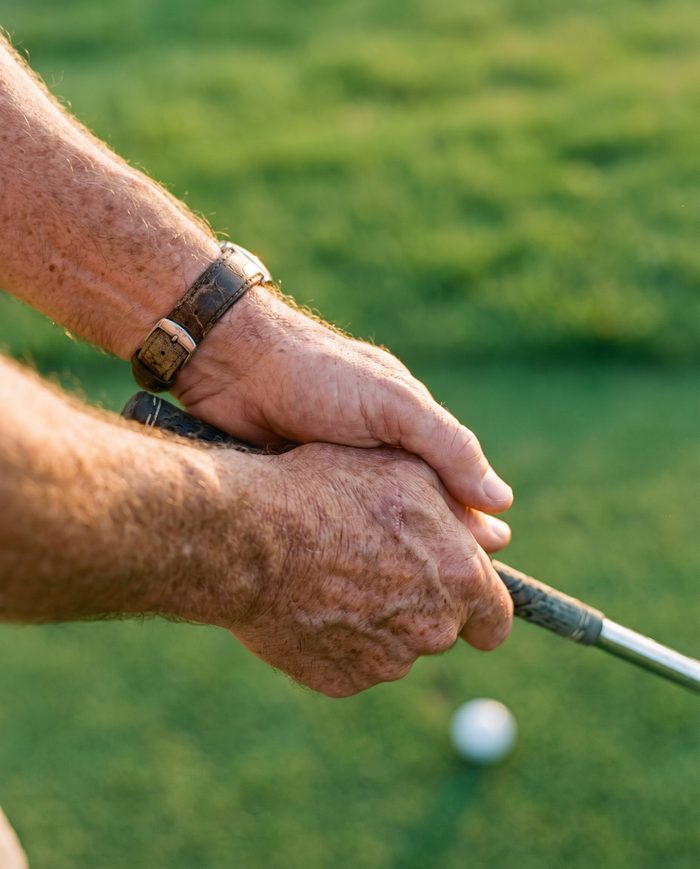 Hands in an interlocked golf grip at the tee