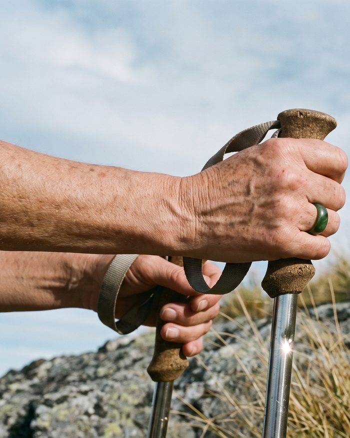 Hands on cork tramping-pole grips above alpine tussock